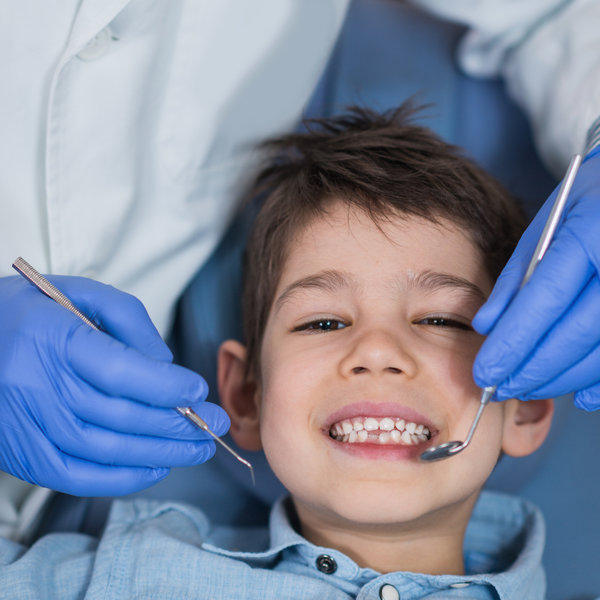 Dentist doing regular dental check-up to little boy.