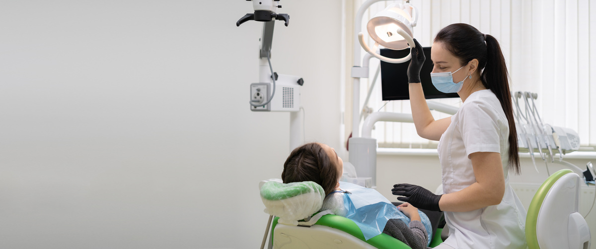Caucasian woman dentist doctor in office with dental equipment microscope treats teeth to patient in chair. Place for your text.