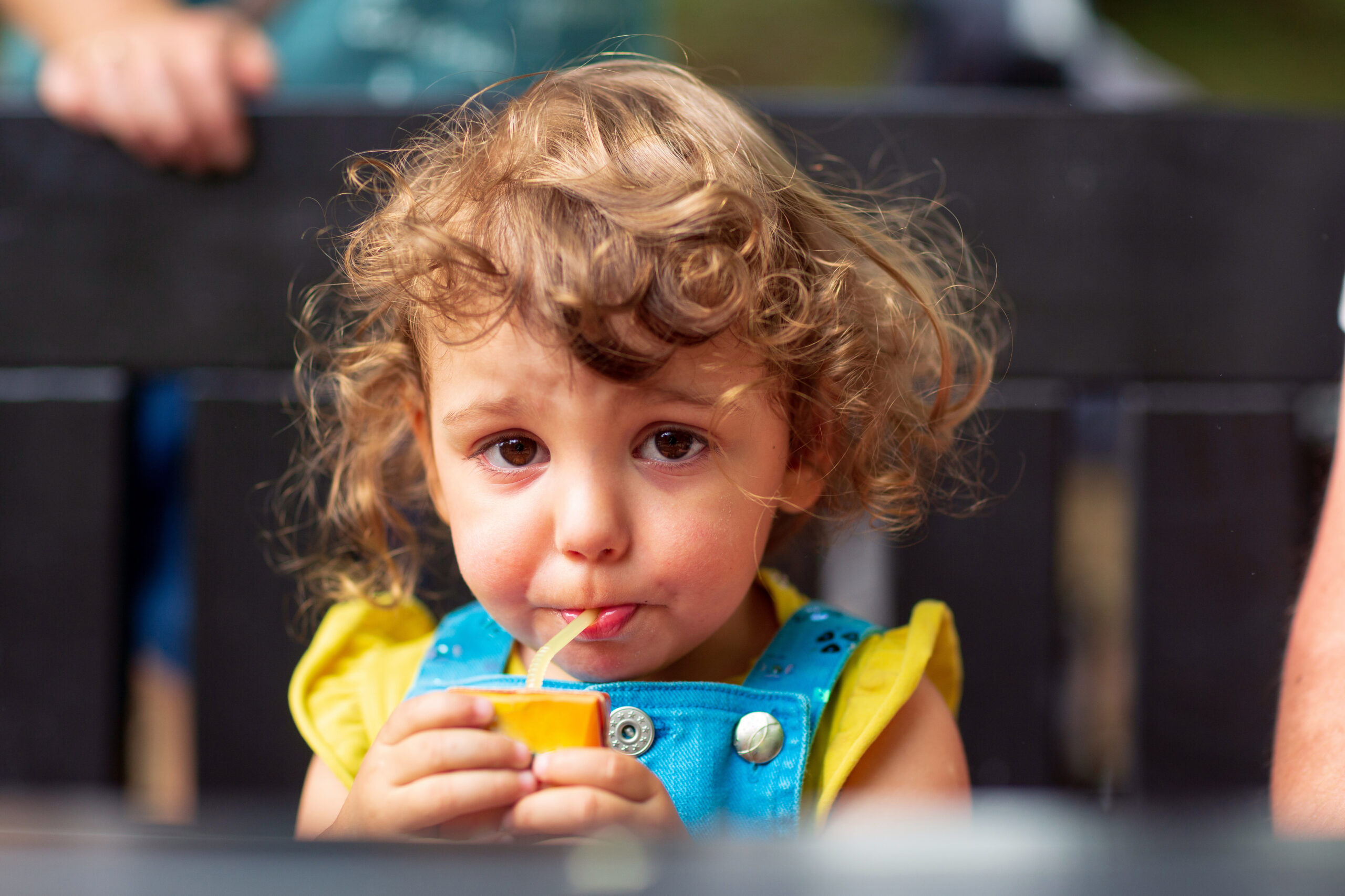 Cute kid girl drinking juice in park