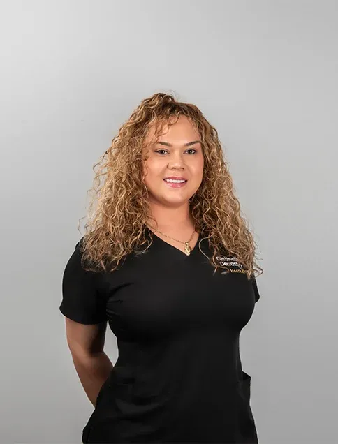 Dental team member Heather in black v-neck uniform against neutral background