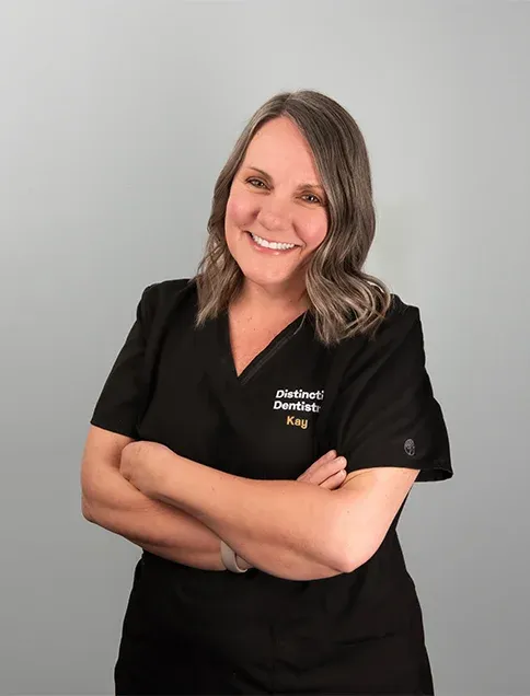 Dental team member Kay in black uniform with arms crossed