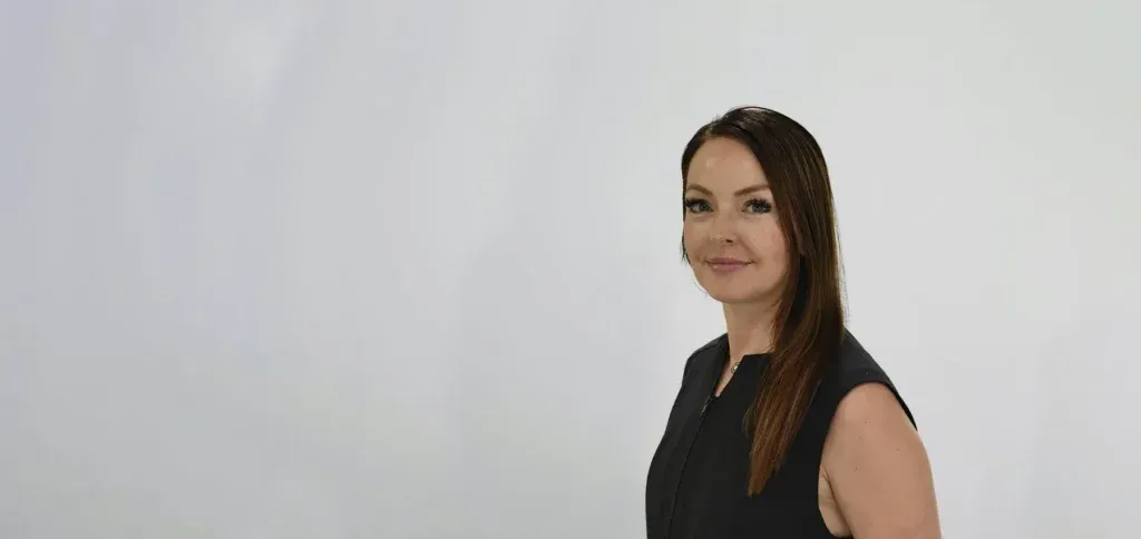 Professional headshot of female dentist in black sleeveless top against neutral background