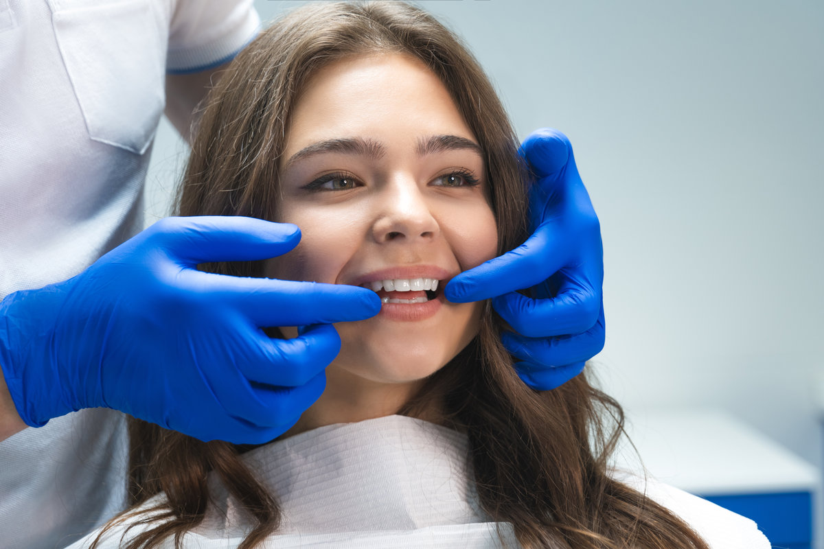 beautiful young brunette woman having examination at dental office while dentist showing whitening results to happy patient.