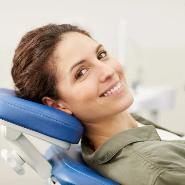 Portrait of smiling young woman lying in dental chair and looking at camera, copy space