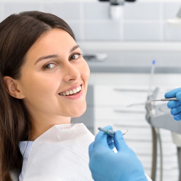 Young happy lady sitting in dentist chair, making regular check up in modern clinic, close up, free space